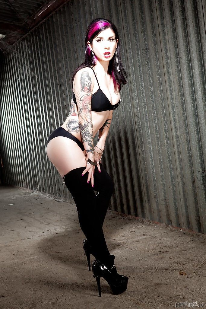 Tattooed vixen in stockings and high heels revealing her tits and gash