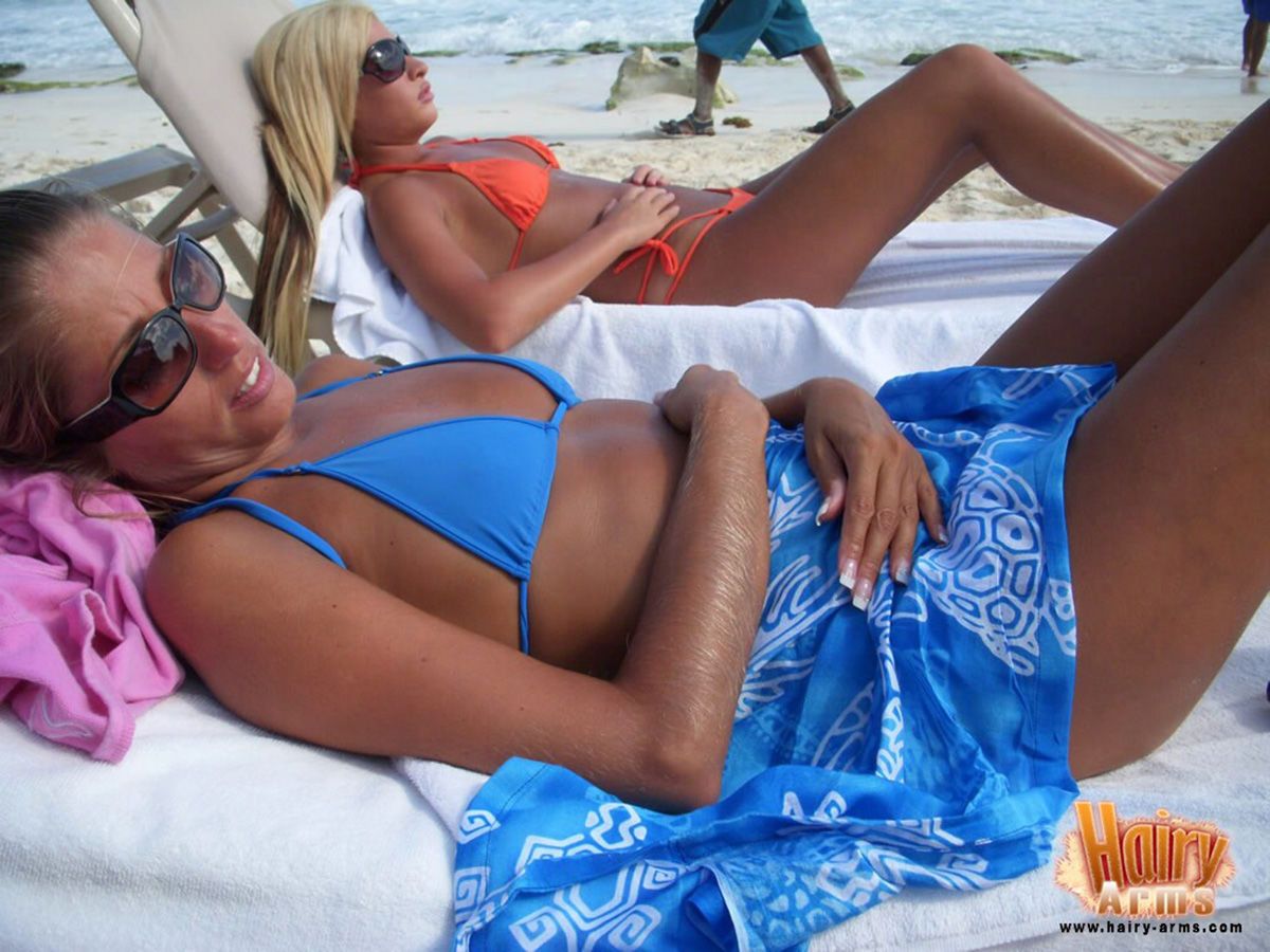 बालों से भरपूर सुनहरे बालों वाली लोरी एंडरसन आराम पर एक समुद्र तट में उसके बिकिनी और धूप का चश्मा