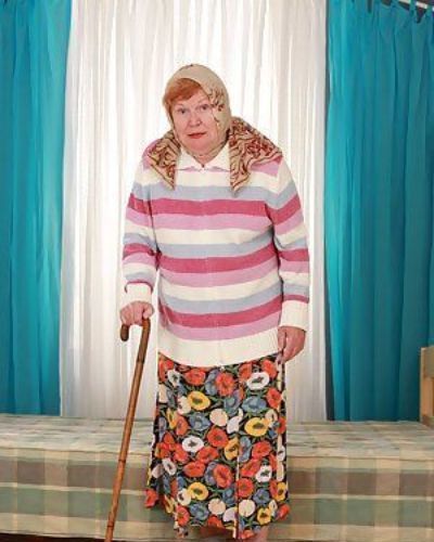 La graisse vieux Granny Alice Avec Canne posant Entièrement Vêtu dans Long Jupe et Chaussettes
