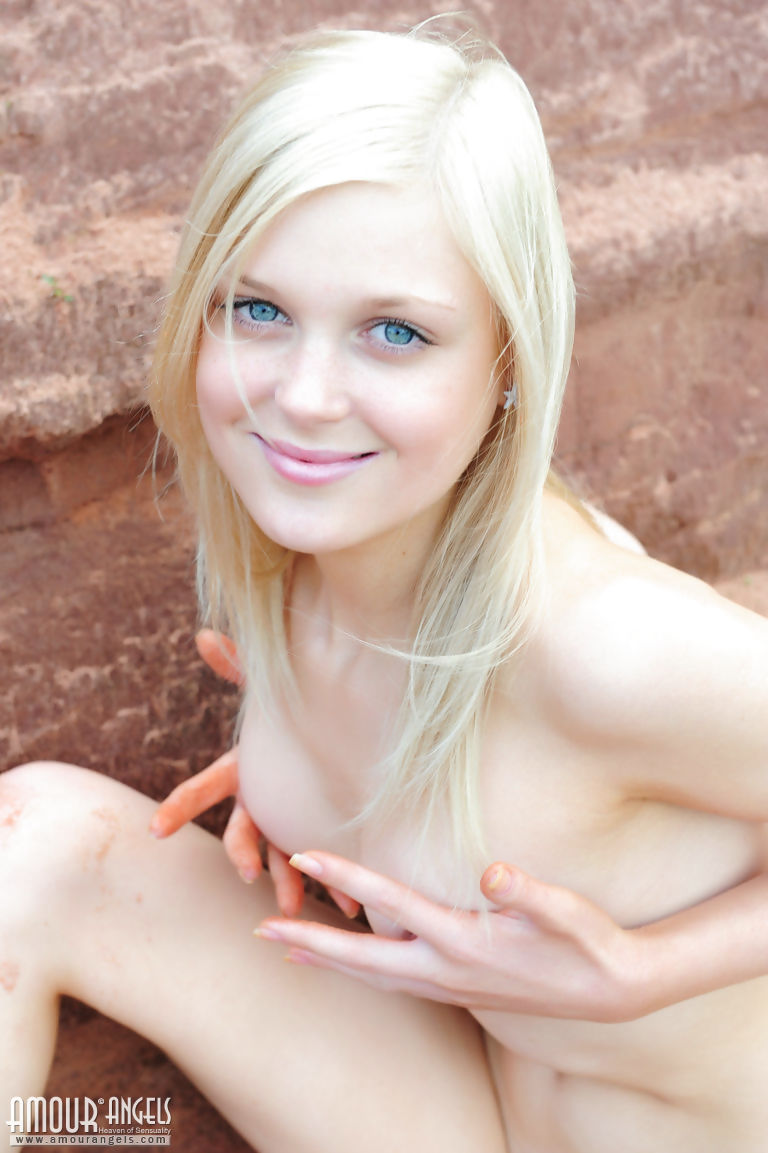 Smiley hot teen Lesia gets on her knees in the sand to spread naked