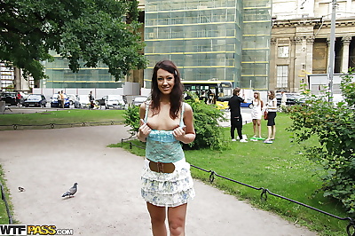 Foxy brunette babe in miniskirt flashing her tits in public place